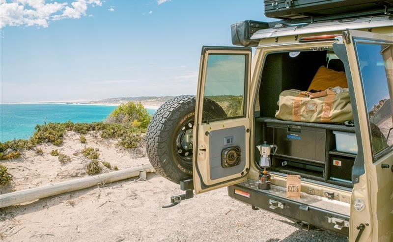 A 4WD with boot doors open stopped in the sand by an Eyre Peninsula beach