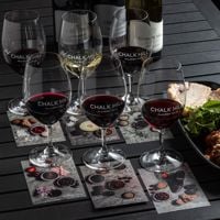 Two bartenders stand behind the bar which has a pitched roof and bottles line the wall behind them. 