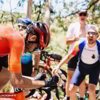 Close up of bike rider racing to the finish line as spectators scream with encouragement from the side lines 