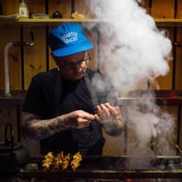 The open kitchen sees one chef plating while the other cooks over the open flame at Shobosho. 