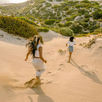 Two girls running down the sand dunes leaving footprints at Sleaford Beach on the Eyre Peninsula 