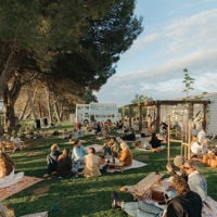 Groups of people lazing on the lawn drinking and eating, with its famous blue double decker tasting bus behind