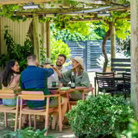 Four friends sitting under the verandah at The Currant Shed cheersing their glasses 