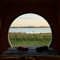 The end of the bed is pushed up against a circular window which shows the wetlands at Coorong.Life