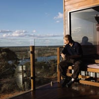 A man sits on the balcony of his Pike River Luxury Villa looking out over lakes